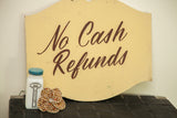 Hand-painted brown cursive text on a vintage duckling yellow wooden sign.