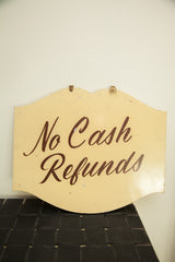 Vintage hand-painted shop sign with its classic brown script and scalloped top.