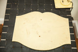 Back of the vintage wood sign showing its unadorned surface and scalloped shape.
