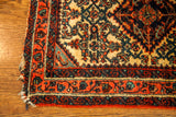 Fringed corner of vintage Persian Engelas rug with plush ivory ground and red, dark blue borders.