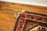 Vintage Persian rug corner, intricate red and dark blue border, plush pile, frayed fringe.