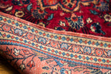 Folded vintage Persian Sarouk rug shows finely detailed red, blue, and beige borders.