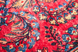 Vintage Sarouk rug detail showing saturated red pile with intricate blue and cream floral patterns.