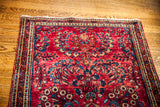 Saturated ruby red field of a vintage Sarouk rug with intricate blue floral border.