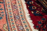 Intricate red and blue geometric patterns along a finely woven Sarouk rug border with soft fringe.