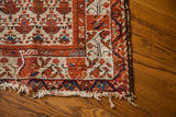 Antique Hamadan rug corner with worn fringe and terracotta rose border.