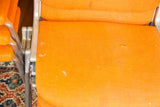 Orange fabric upholstery showing wear with dull aluminum frame on vintage DSC chair.