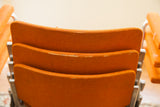 Stacked orange fabric chair backs with visible edge wear from Castelli DSC.