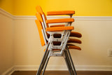 Stacked orange Pirelli by Castelli DSC chairs, emphasizing aluminum frames and rare armrests.