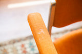 Textured orange armrest detail of a vintage Pirelli Castelli DSC chair, showing wear.
