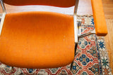 Orange upholstered Pirelli DSC chair seat and armrest, aluminum frame, over a patterned rug.