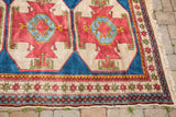 Geometric red, plum, blue, and beige patterns on hand-knotted Turkish rug border with fringe.