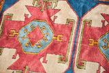 Geometric plum red, soft blue, and cream patterns on a vintage Turkish rug.