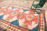 Vibrant geometric patterns in plum-red, sky blue, and cream of a hand-knotted vintage Turkish rug.