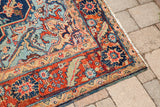 Saturated blue, rust, and mint green patterns on a vintage Heriz rug corner.