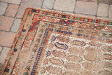 Antique Caucasian rug corner with distressed ivory field and repeating boteh motifs.