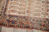 Geometric borders and distressed ivory field with boteh motifs on an antique Caucasian rug.
