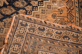 Antique tribal rug's woven edge, showing geometric pattern and visible tear.