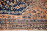 Antique Southwest Persian tribal rug's storied end, with geometric deep blue and earth-toned borders.