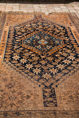 Lower edge of antique Southwest Persian rug, featuring geometric earth tone and navy motifs.