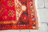 Hand-knotted corner of a Red Turkish Yastik rug featuring vibrant geometric motifs and fringe.
