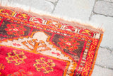 Red, orange, and cream geometric border with fringe on a vintage Turkish Yastik accent rug.