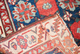 Antique Persian rug folded, revealing deep red floral pile, natural foundation, and careful reweaving.