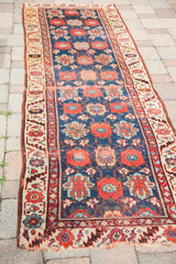 Articulated Veramin floral motifs in red, light blue, and cream on a navy antique Persian runner.