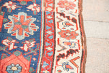 Detail of antique Persian Veramin runner, showing navy field's large floral motif and red, ivory border.