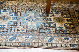 Detail of tribal Lesghi geometric patterns in blue, cream, and brown on a vintage Kazak rug.