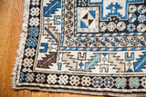 Vintage tribal Caucasian rug corner, showing Lesghi patterns in blue, beige, and brown.