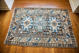 Corner detail of vintage Caucasian rug, showing geometric blue and cream Lesghi motifs with fringed edge.