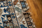 Geometric blue and beige tribal Lesghi pattern on the vintage rug's edge with a visible small split.