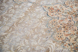Distressed vintage Tabriz rug detail: faded ivory field with rust and blue floral pattern.