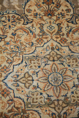 Close-up of vintage Tabriz rug's distressed pile with ivory, rust, and blue curvilinear covered field design.