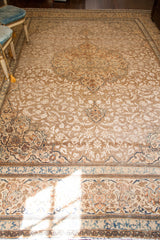 Distressed texture of a vintage Tabriz Persian rug showing ivory, rust, blue floral motifs.