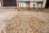 Distressed Tabriz Persian rug with ivory, rust, silver, and blue floral medallion.