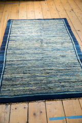 Striated indigo running water motif of the antique Chinese rug, showing its dark blue border and fringe.