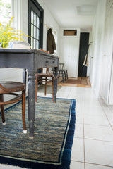 Unusual striated indigo motif and deep blue border on the hand-knotted rug.
