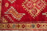 Vintage Turkish rug detail: deep red field, gold tribal motifs, and a floral-patterned border.