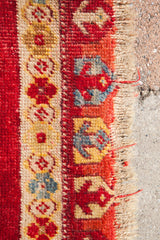 Turkish rug border of deep red, gold, blue geometric motifs, and hand-knotted fringe.