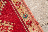 Hand-knotted vintage Turkish rug edge, deep red field, creamy border with blue floral motifs.