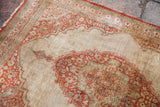 Detailed corner of an antique silk Tabriz mat showing the fine weave and rust, ivory, and green motifs.