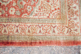 Detail of an antique silk Tabriz rug border with intricate motifs in rust, soft green, and hints of light purple.
