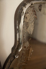 Distressed silvering and curvy beveled glass edge of a vintage Deco mirror with rhinestone.