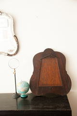 Back of a vintage 1930s bell-shaped Deco mirror, featuring distressed dark wood.