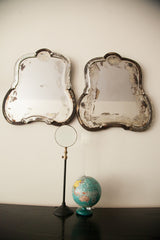 Lower portions of two bell-shaped Art Deco mirrors with distressed glass and dark frames.
