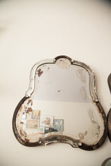 Distressed bell-shaped Art Deco mirror with weathered beveled glass and dark frame.