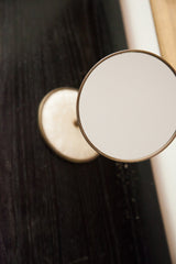 Circular mid-century mirror with aged bronze-toned frame and pale surface.