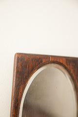 Upper corner of the vintage wood mirror, showing aged patina and beveled glass detail.